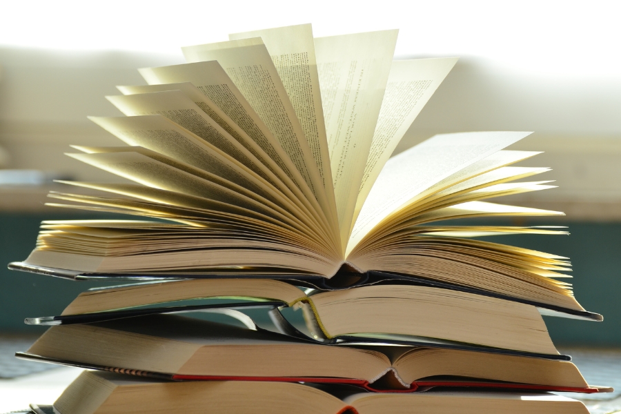 pile of books with top book fanned open