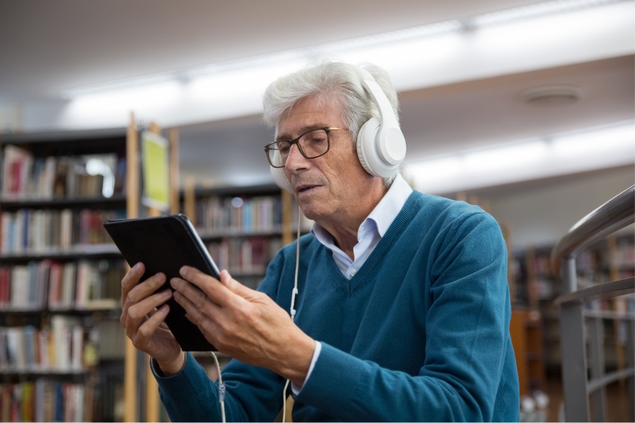Man listening to audio book in library