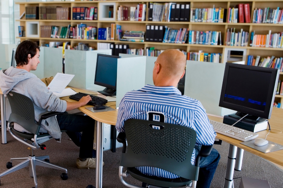 Men in library using computers