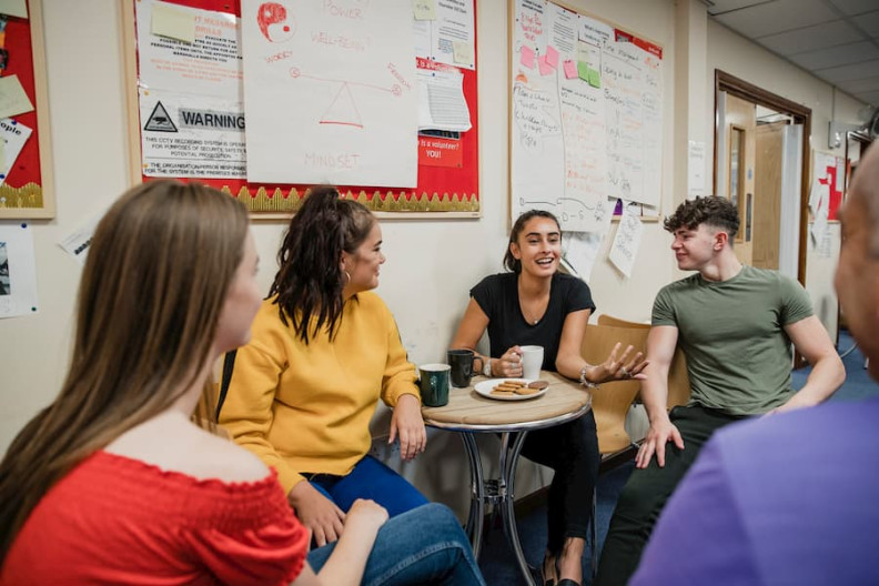 Wellbeing support group stock A group of young people talking over coffee