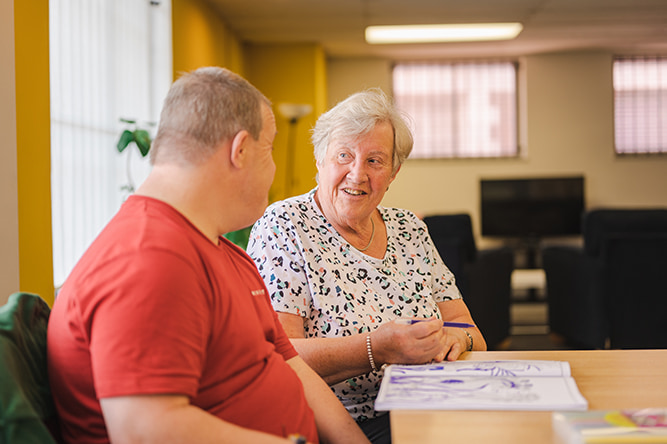An older woman and a young man sat at a table chatting