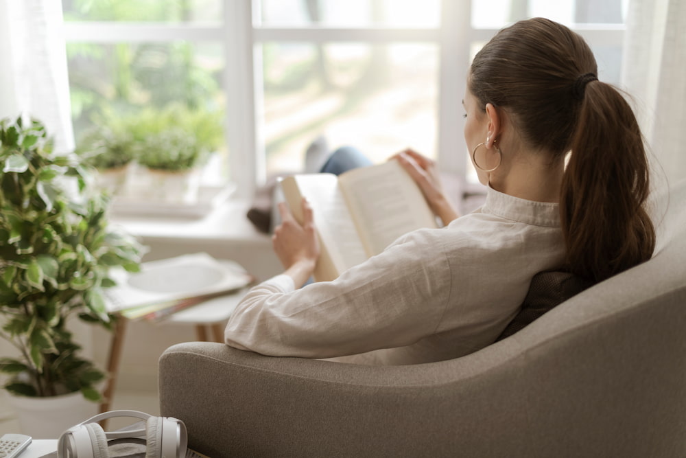 Woman reading a book stock resize Woman sat in a chair reading a book