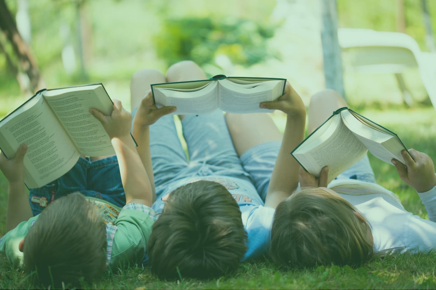 Children reading books outdoors green overlay 3x2 resize Photo of three children reading books outdoors with a green overlay