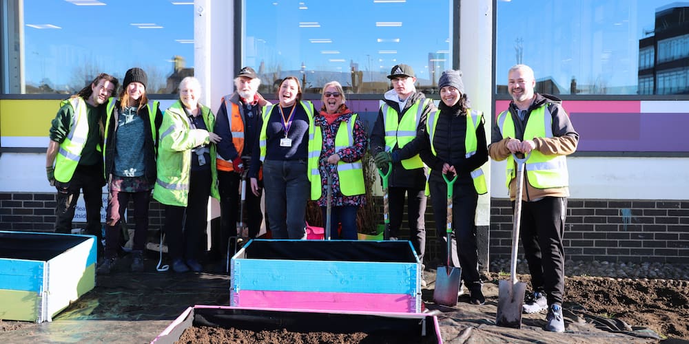 A group of people in hi-vis jackets standing with shovels in the Lowestoft Library garden