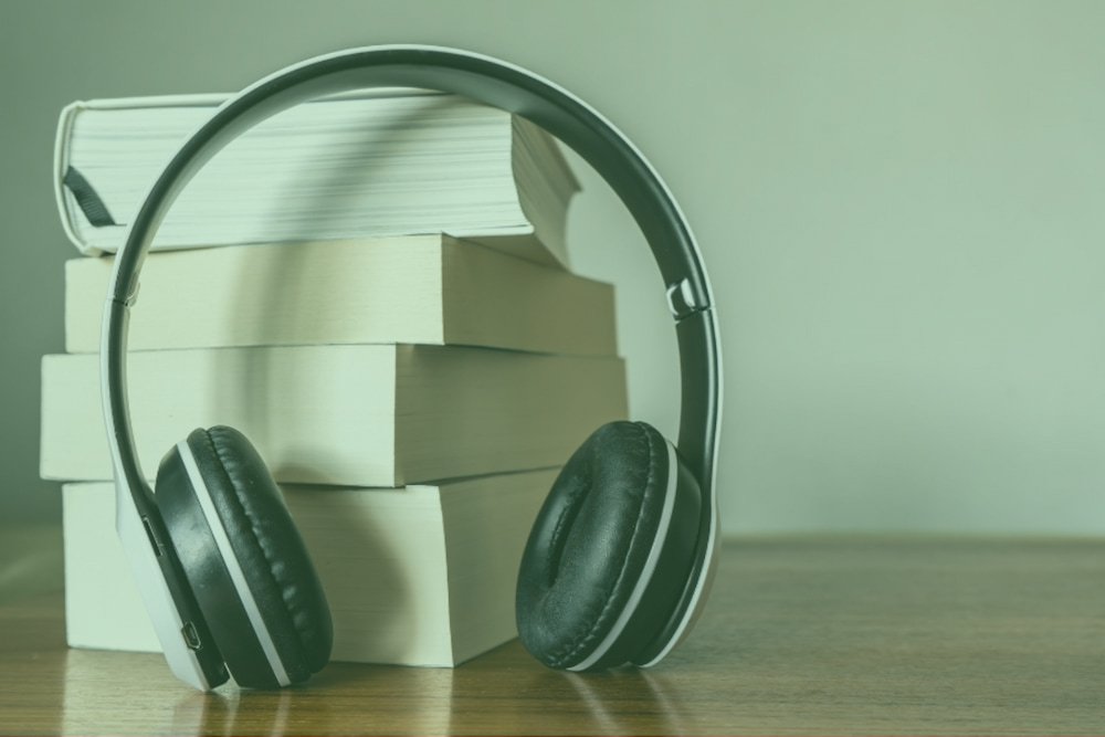 Audiobooks green overlay resize Stack of books next to a pair of headphones, with a green overlay
