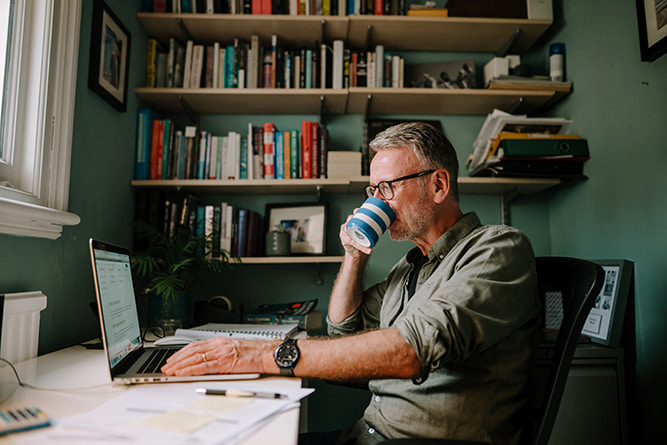 Man using computer in home office stock resize A man browsing on a laptop in a home office