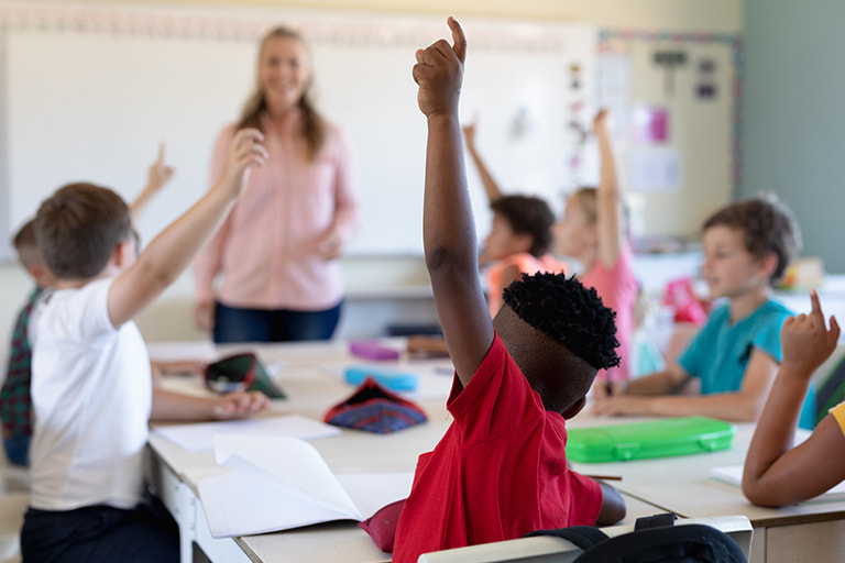 Preparing for School stock Children in a classroom raising their hands