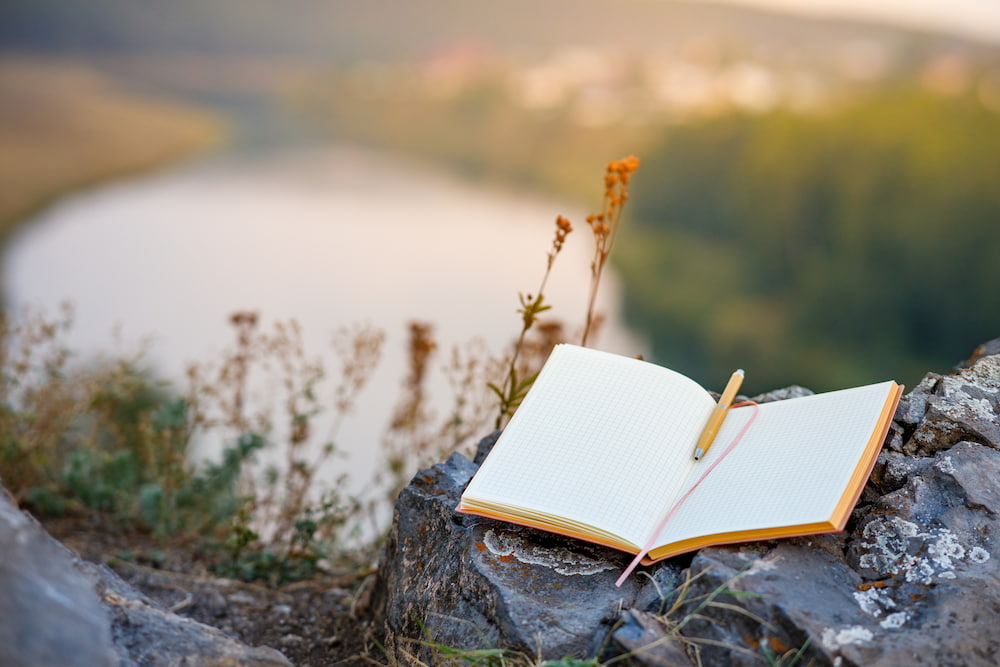 Photo of an open book overlooking a river and forests