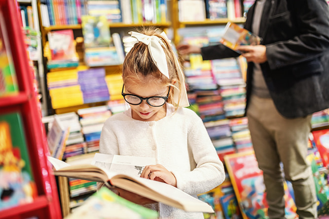 Young girl reading book in the library stock resize A young girl reading a book in the library