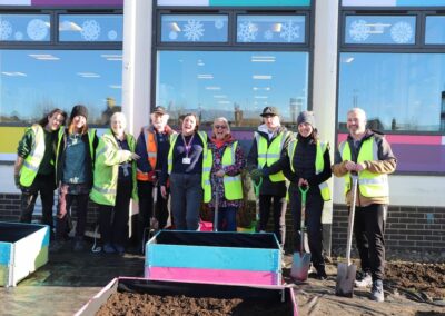 A group of people in hi-vis jackets standing with shovels in the Lowestoft Library garden