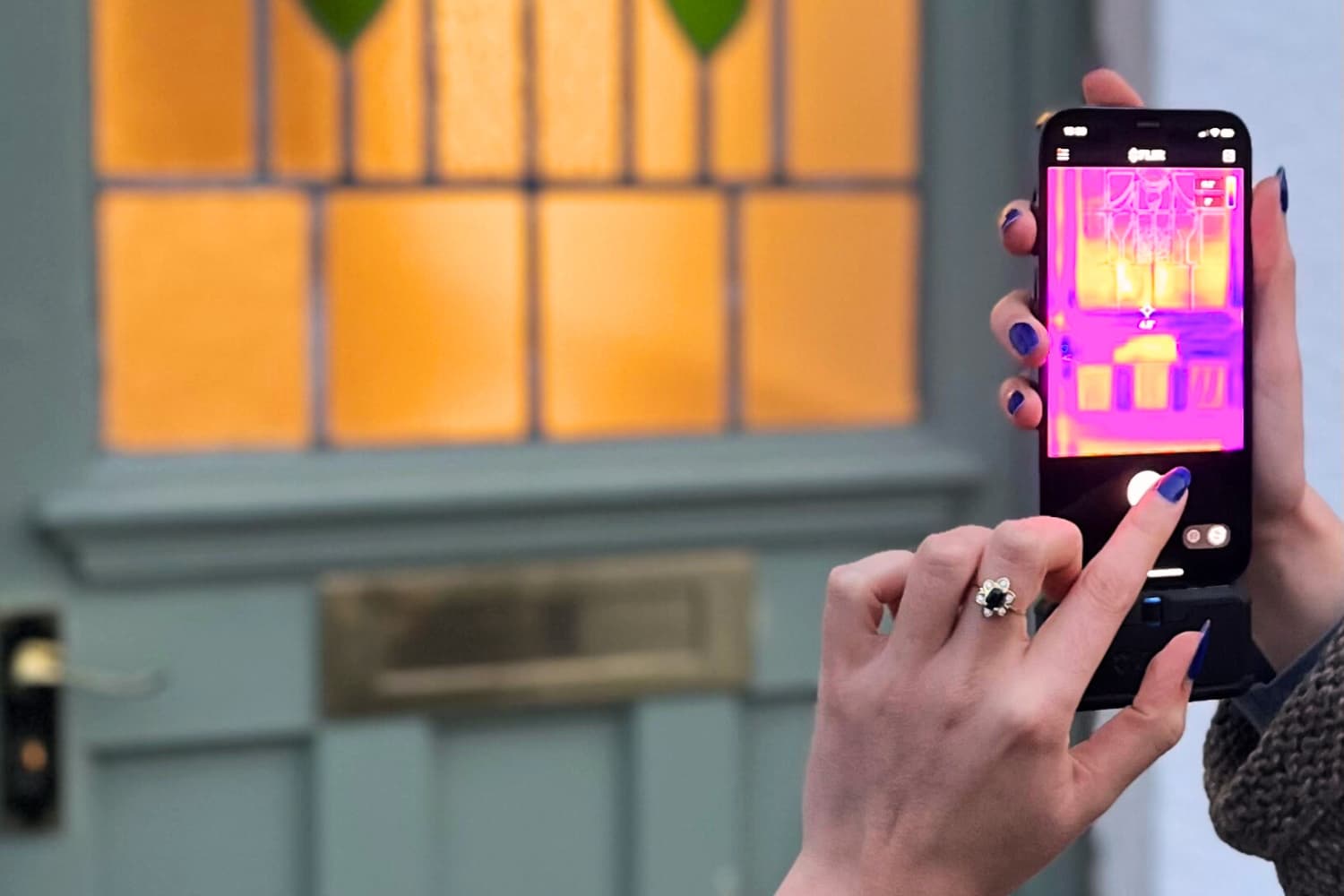 A person using a thermal imaging camera on their phone to see where heat is leaking from their front door