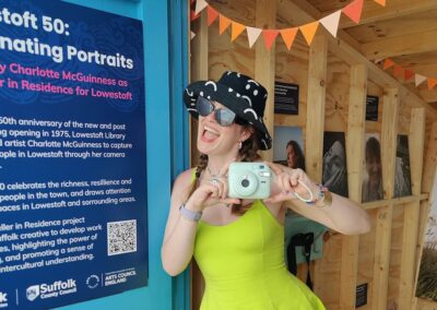 Charlotte McGuinness holding her polaroid camera in the beach hut at First Light Festival.