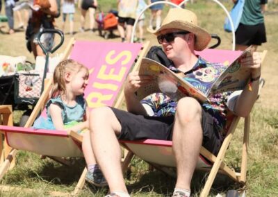 A dad and his daughter reading an oversized book on a deckchair