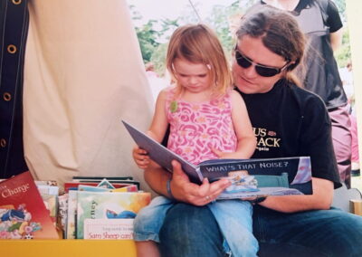 A dad reading to his daughter in the libraries tent